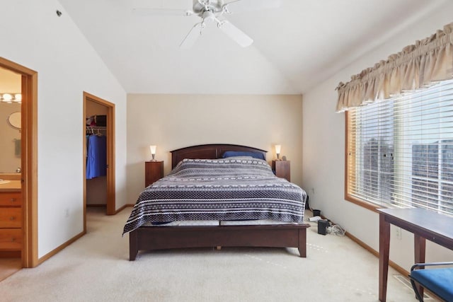 bedroom featuring a spacious closet, light colored carpet, lofted ceiling, a closet, and ensuite bath