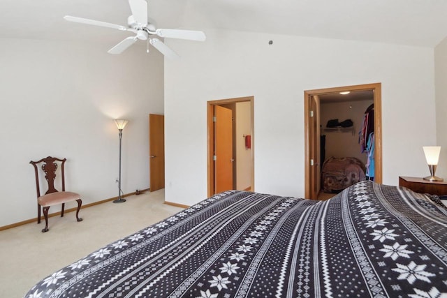 carpeted bedroom featuring a walk in closet, baseboards, a closet, and high vaulted ceiling