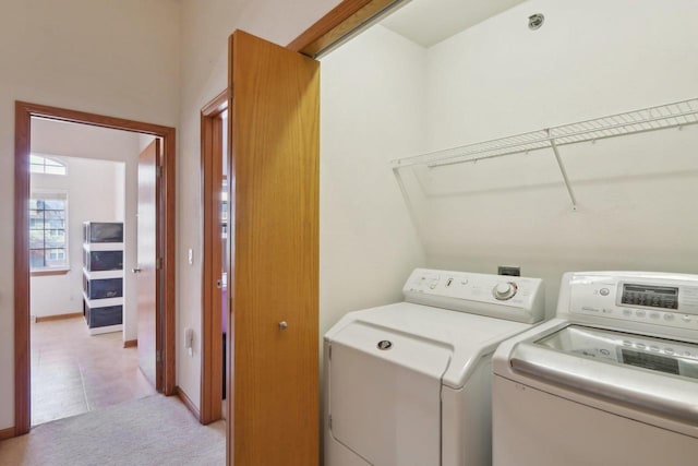 laundry area featuring laundry area, light colored carpet, independent washer and dryer, and baseboards