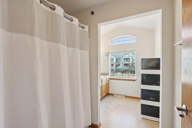 full bath featuring vanity, a shower with shower curtain, baseboards, visible vents, and lofted ceiling