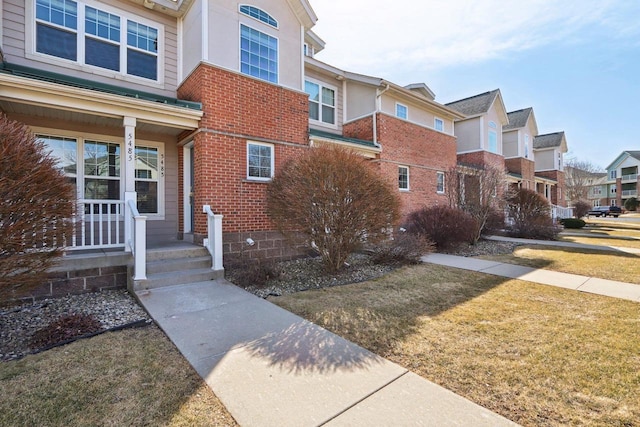 view of side of property with a yard, brick siding, and a residential view