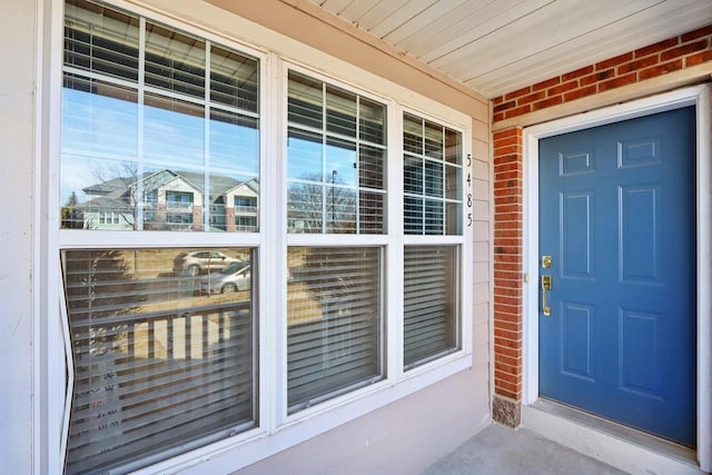 view of exterior entry with covered porch and brick siding