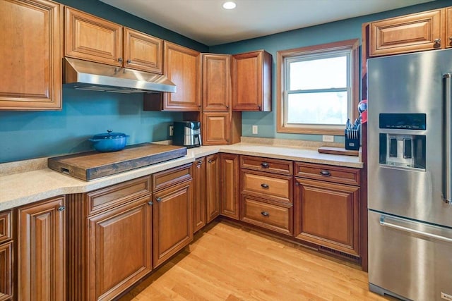 kitchen featuring black electric stovetop, stainless steel fridge, and light hardwood / wood-style floors