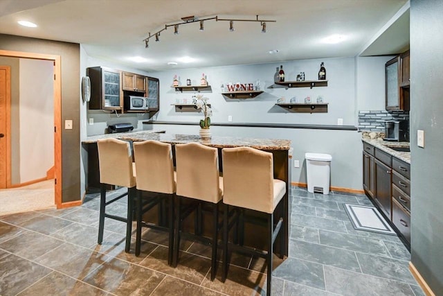 kitchen with light stone countertops, a breakfast bar, and decorative backsplash