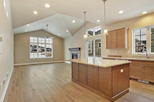 kitchen with pendant lighting, a fireplace, sink, a center island, and light stone counters