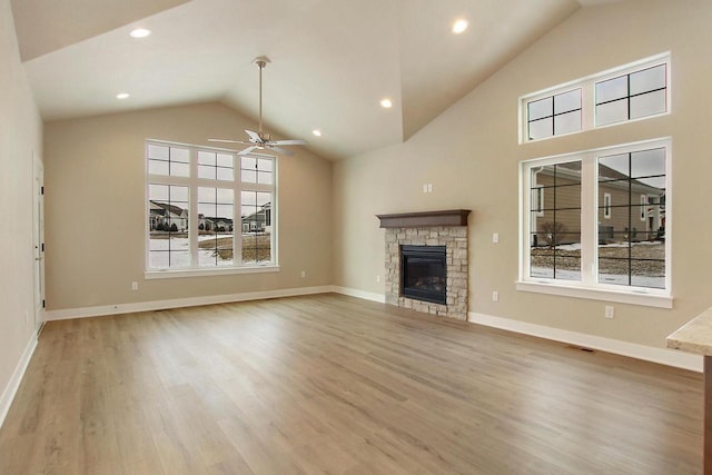 unfurnished living room with ceiling fan, a healthy amount of sunlight, a fireplace, and light hardwood / wood-style flooring