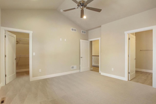 unfurnished bedroom with high vaulted ceiling, a spacious closet, light colored carpet, ceiling fan, and a closet