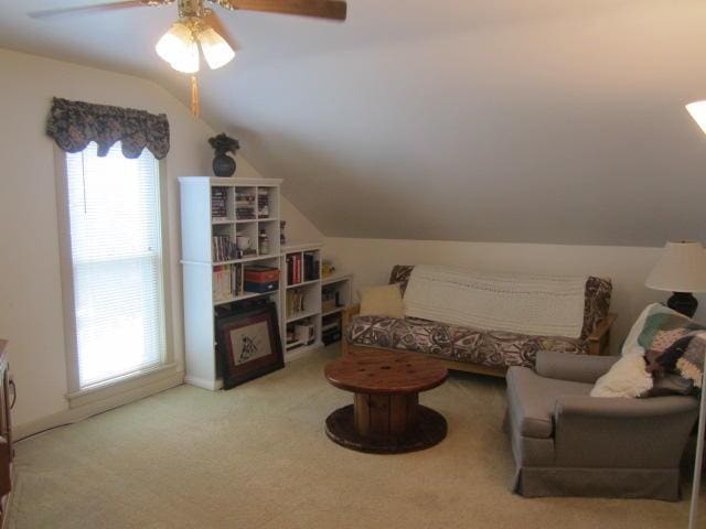 living area with ceiling fan, light colored carpet, and vaulted ceiling