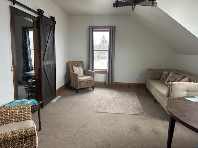 interior space with vaulted ceiling, a barn door, and light carpet