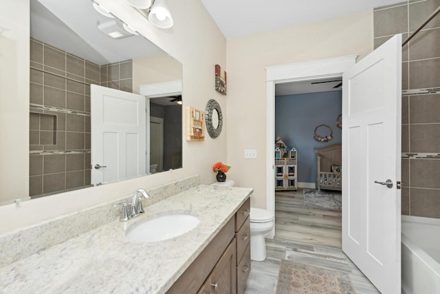 full bathroom with ceiling fan, tiled shower / bath, vanity, and toilet