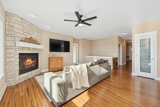 living room featuring hardwood / wood-style flooring, ceiling fan, and a fireplace