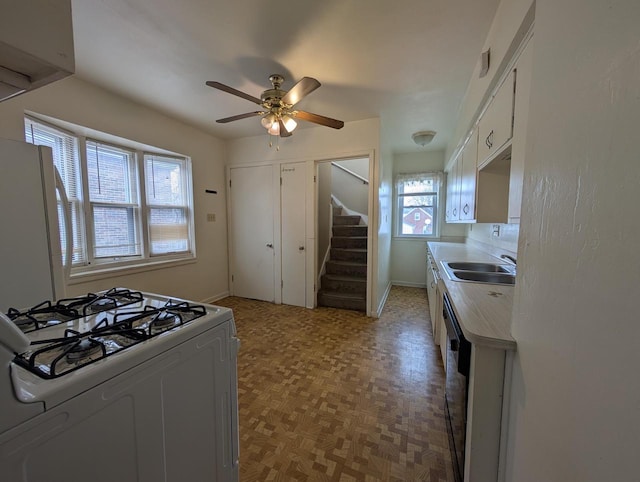 kitchen with sink, white appliances, light parquet floors, ceiling fan, and white cabinets