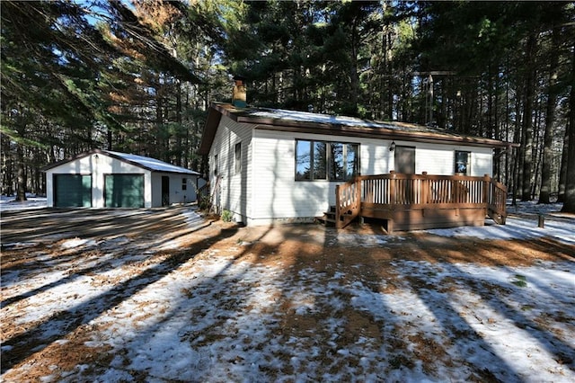 view of front facade featuring a garage, a wooden deck, and an outbuilding