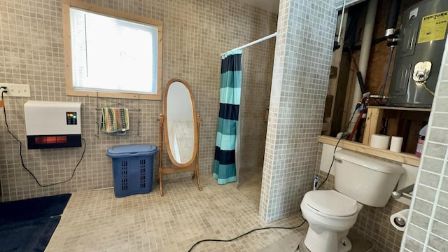 bathroom with a shower with shower curtain, toilet, tile patterned flooring, and tile walls