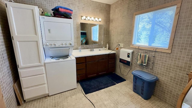 bathroom with stacked washer and dryer, tile walls, tile patterned flooring, vanity, and heating unit