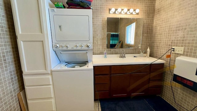 bathroom featuring tasteful backsplash, stacked washing maching and dryer, tile walls, and vanity