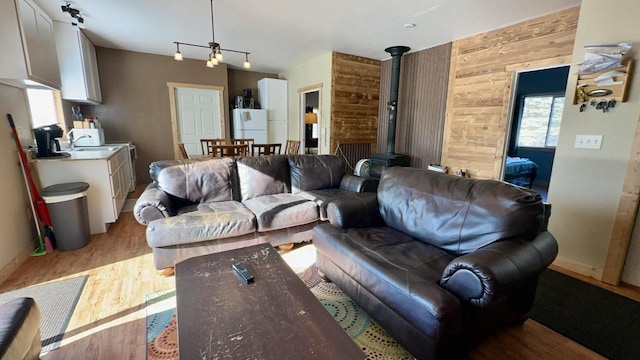 living room featuring a wood stove, light hardwood / wood-style floors, and wood walls