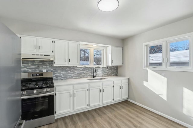 kitchen with sink, backsplash, white cabinets, and appliances with stainless steel finishes