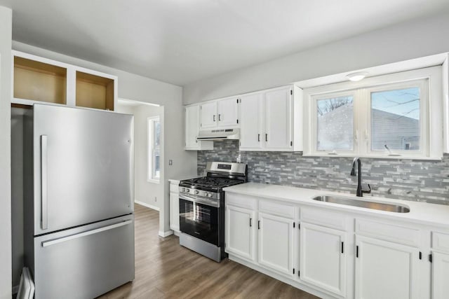 kitchen with sink, appliances with stainless steel finishes, hardwood / wood-style floors, tasteful backsplash, and white cabinets