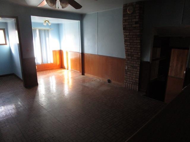 spare room with ceiling fan and wood walls