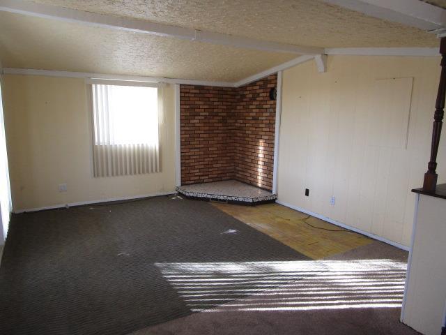 spare room with dark hardwood / wood-style floors, a textured ceiling, and vaulted ceiling with beams