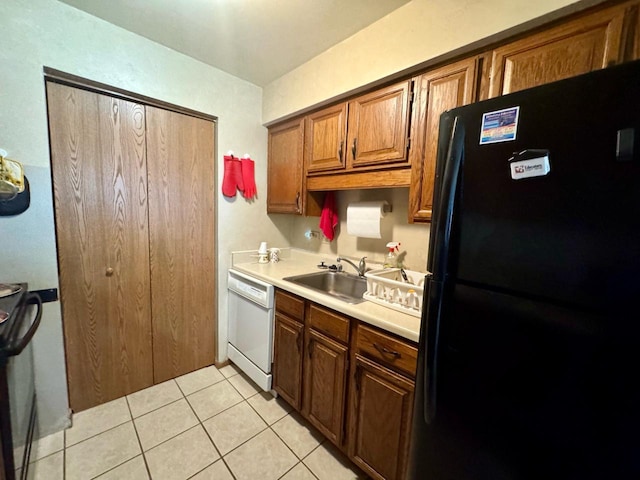 kitchen with dishwasher, black fridge, sink, and light tile patterned floors