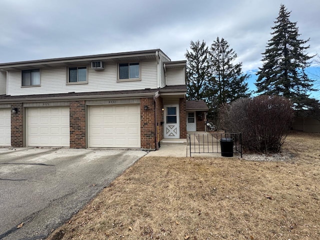 front facade with a garage, a wall unit AC, and a front lawn