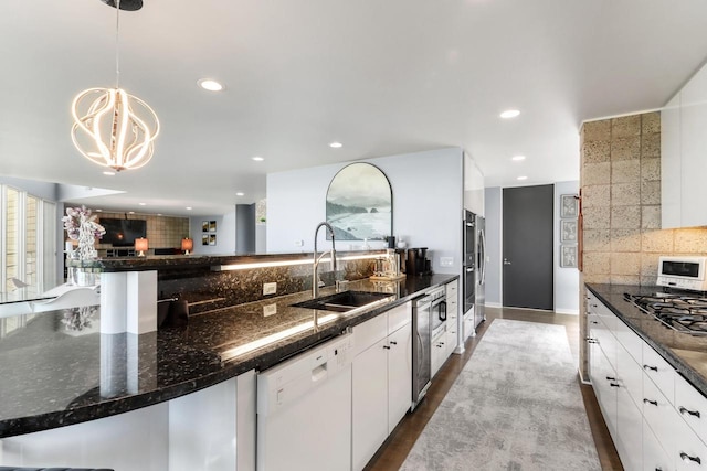 kitchen featuring sink, white appliances, dark stone countertops, white cabinets, and decorative light fixtures