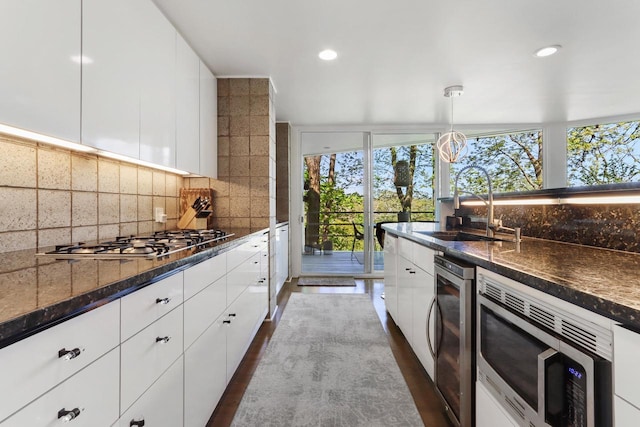 kitchen with appliances with stainless steel finishes, pendant lighting, tasteful backsplash, sink, and white cabinets