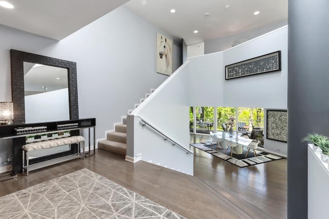 staircase with wood-type flooring and a high ceiling