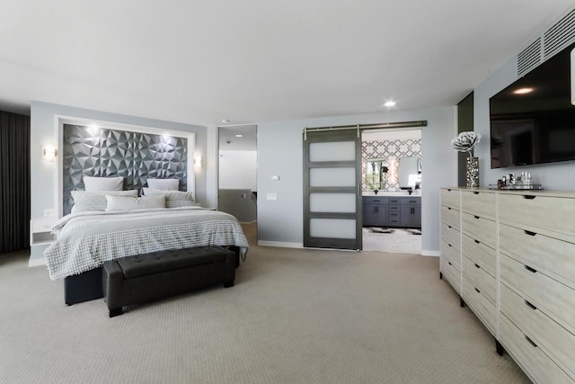 bedroom with light colored carpet, connected bathroom, and a barn door