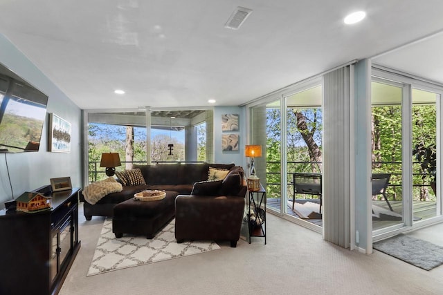 living room with a wealth of natural light, light colored carpet, and a wall of windows