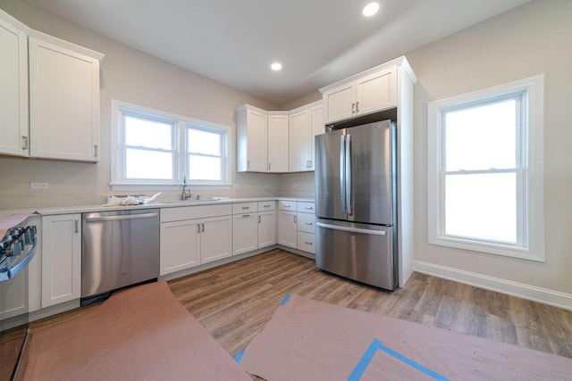 kitchen with white cabinetry, sink, stainless steel appliances, and light hardwood / wood-style floors