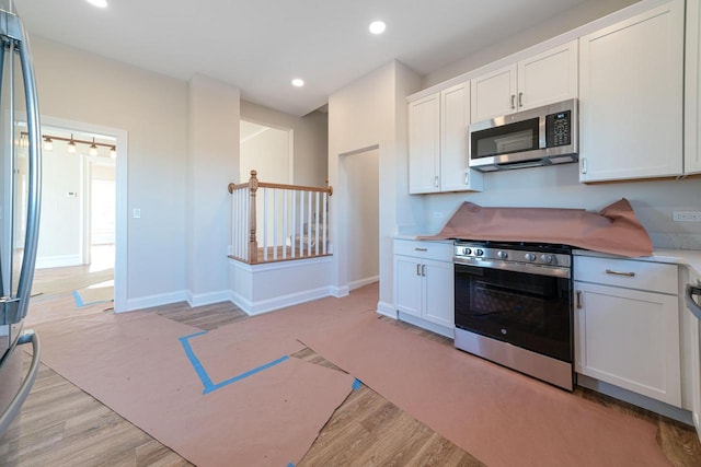 kitchen with white cabinetry, light hardwood / wood-style flooring, and appliances with stainless steel finishes