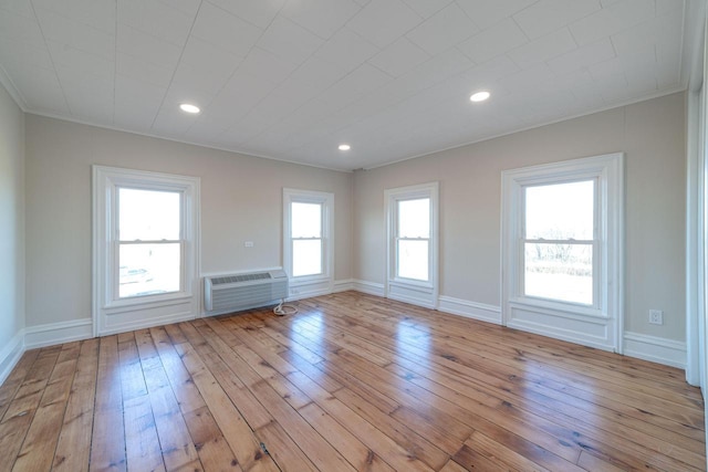 unfurnished room with a wall mounted air conditioner, crown molding, a healthy amount of sunlight, and light wood-type flooring