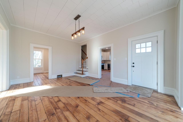 foyer entrance with crown molding and light hardwood / wood-style flooring