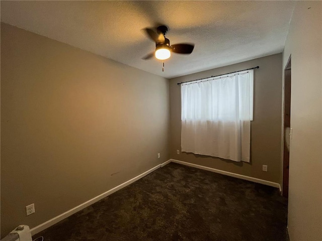 spare room featuring ceiling fan, dark carpet, and a textured ceiling