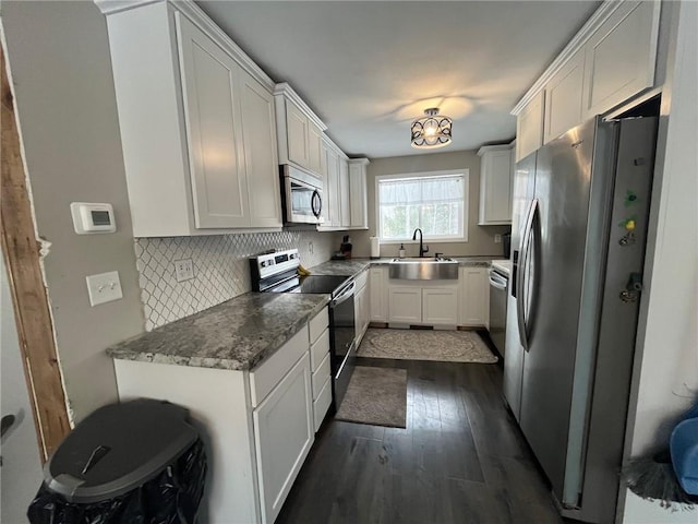 kitchen featuring dark wood-type flooring, sink, white cabinetry, tasteful backsplash, and appliances with stainless steel finishes