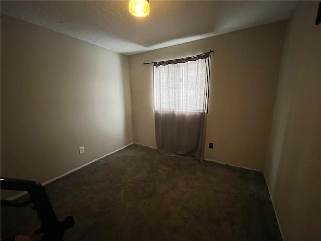 unfurnished room with dark colored carpet