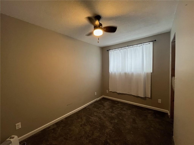 spare room featuring dark colored carpet, ceiling fan, and a textured ceiling