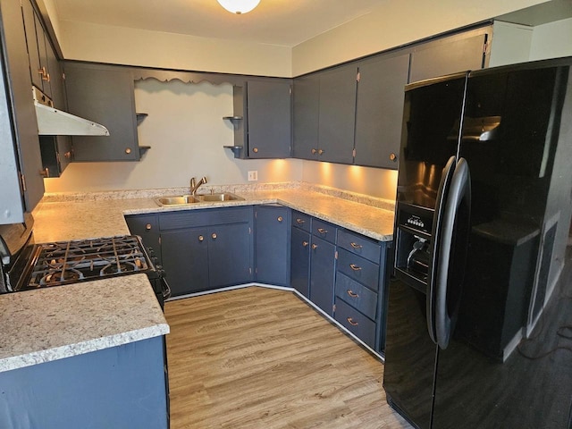 kitchen featuring sink, gas range, black fridge, blue cabinetry, and light wood-type flooring