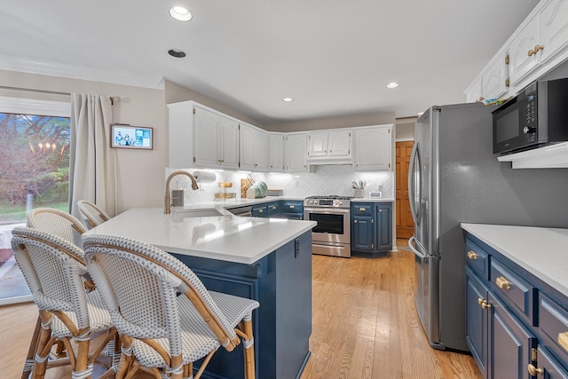 kitchen with appliances with stainless steel finishes, blue cabinets, sink, white cabinets, and kitchen peninsula