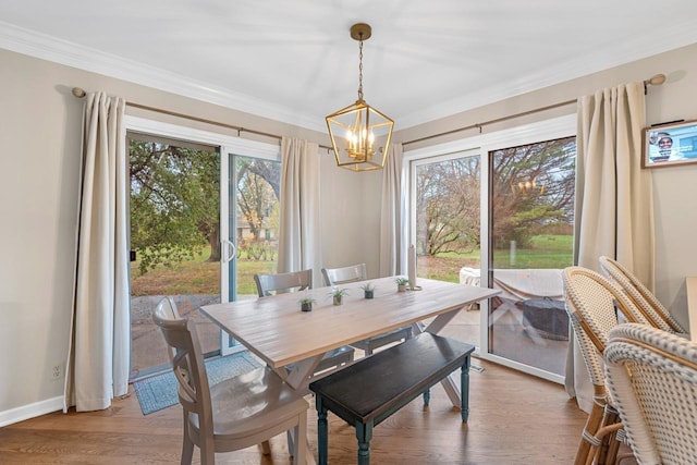 dining room with crown molding, light hardwood / wood-style floors, and a notable chandelier