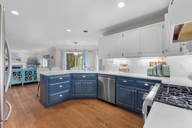 kitchen featuring blue cabinetry, decorative light fixtures, light hardwood / wood-style flooring, appliances with stainless steel finishes, and white cabinets