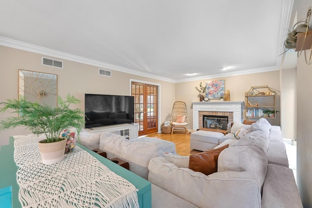 living room with french doors, ornamental molding, wood-type flooring, and a brick fireplace