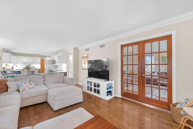 living room with hardwood / wood-style flooring, ornamental molding, and french doors