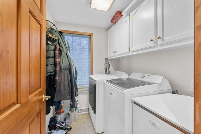 clothes washing area featuring light tile patterned flooring, cabinets, and washer and dryer