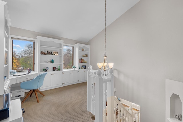 carpeted home office with high vaulted ceiling and an inviting chandelier