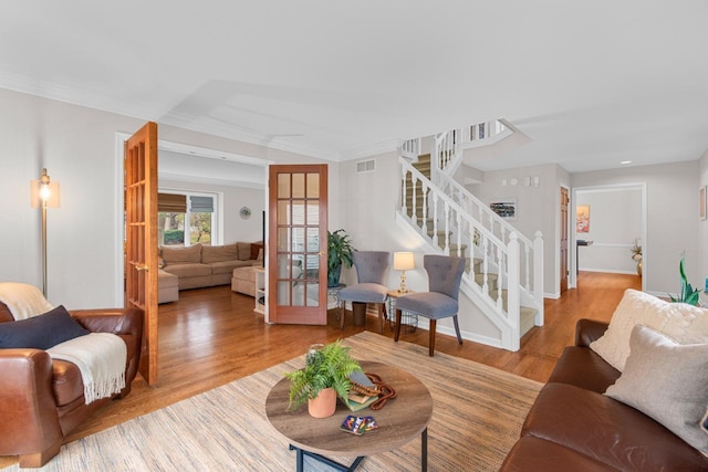 living room featuring ornamental molding, light hardwood / wood-style floors, and french doors