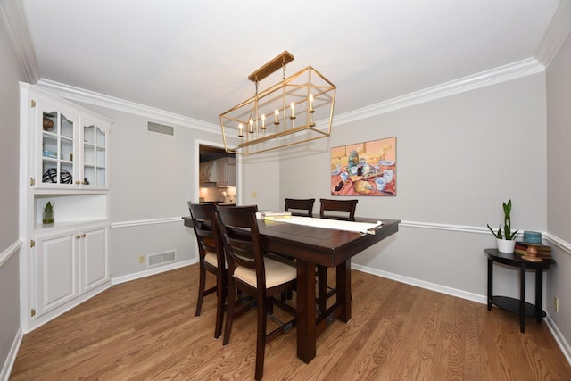 dining area with an inviting chandelier, dark wood-type flooring, and ornamental molding